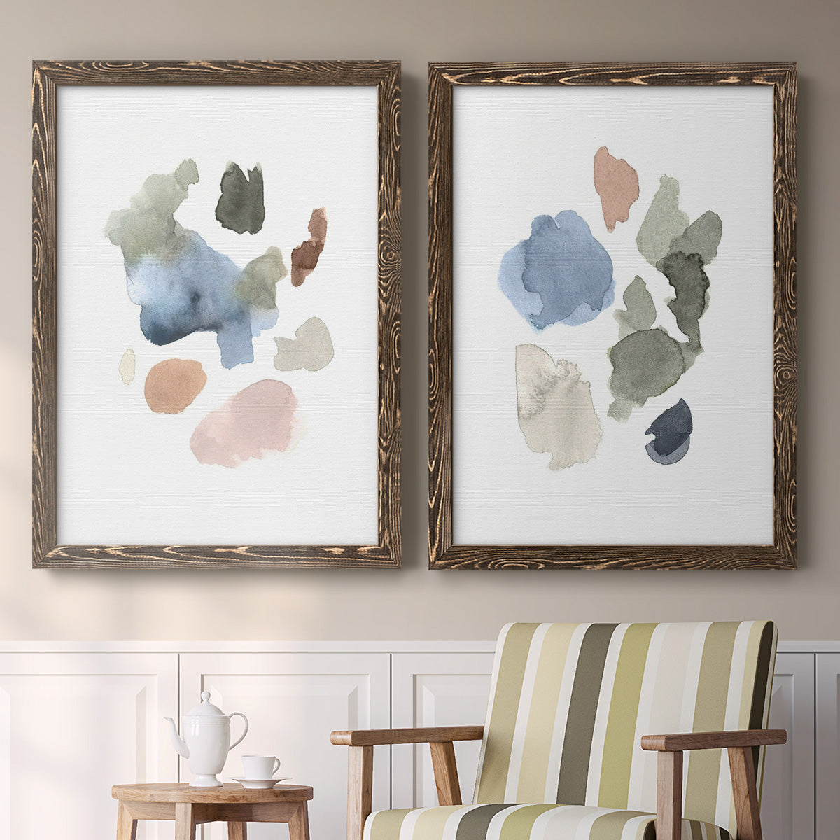 Set of two walnut barnwood framed canvas prints depicting two airy minimalist abstracts featuring scattered translucent watercolor shapes above a sideboard in a cozy sitting room.