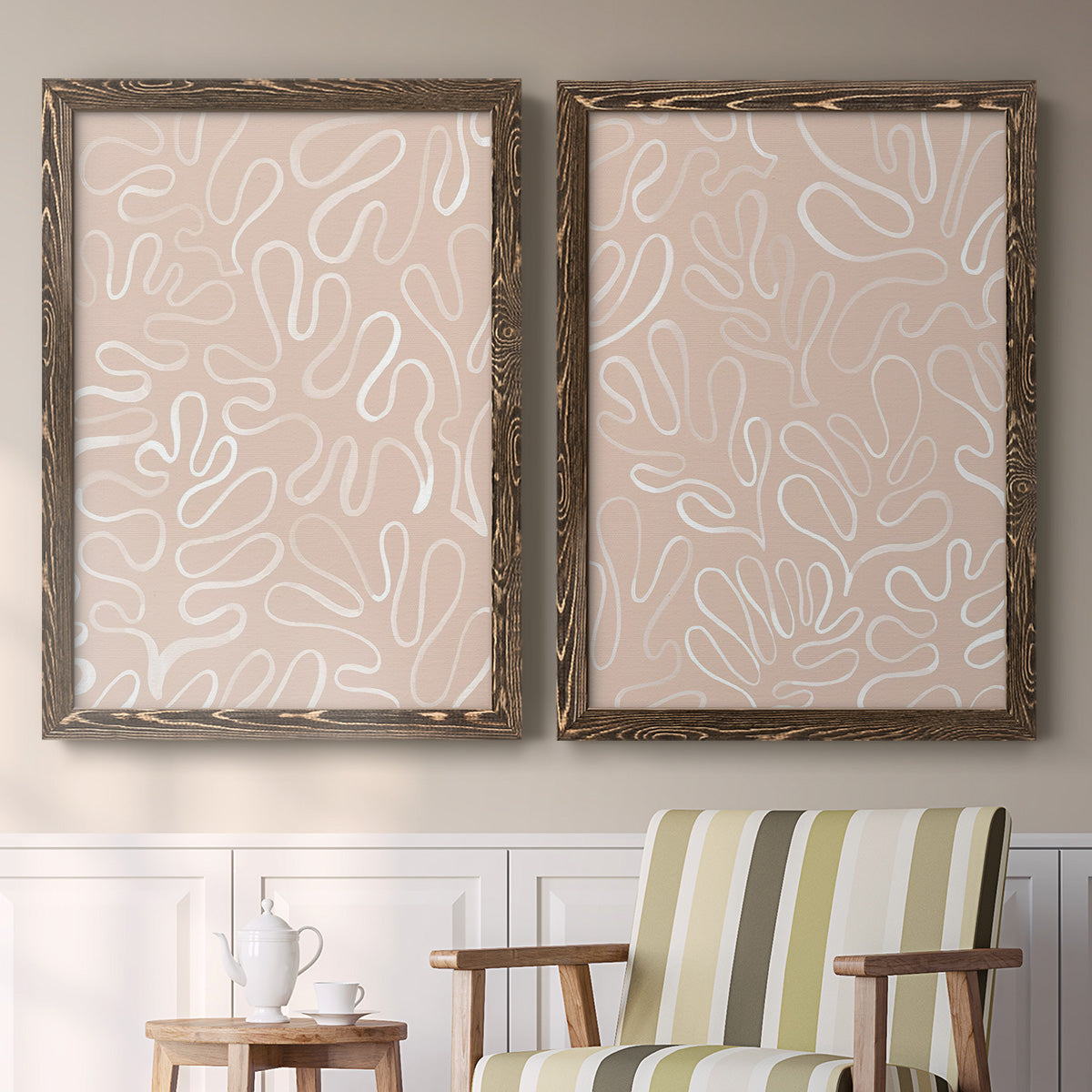 Set of two walnut barnwood framed canvas prints depicting two graphic botanical pattern abstracts featuring continuous white organic lines over solid ochre and blush fields above a sideboard in a cozy sitting room.