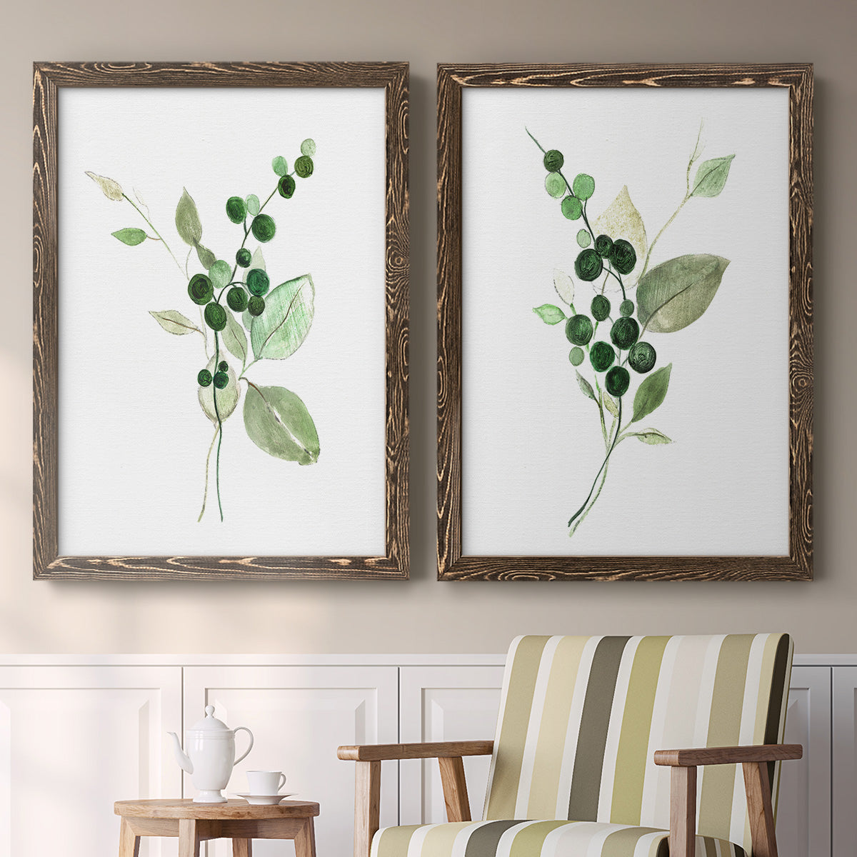 Set of two walnut barnwood framed canvas prints depicting two rustic watercolor botanical studies featuring green berry sprigs and pale leaves above a sideboard in a cozy sitting room.