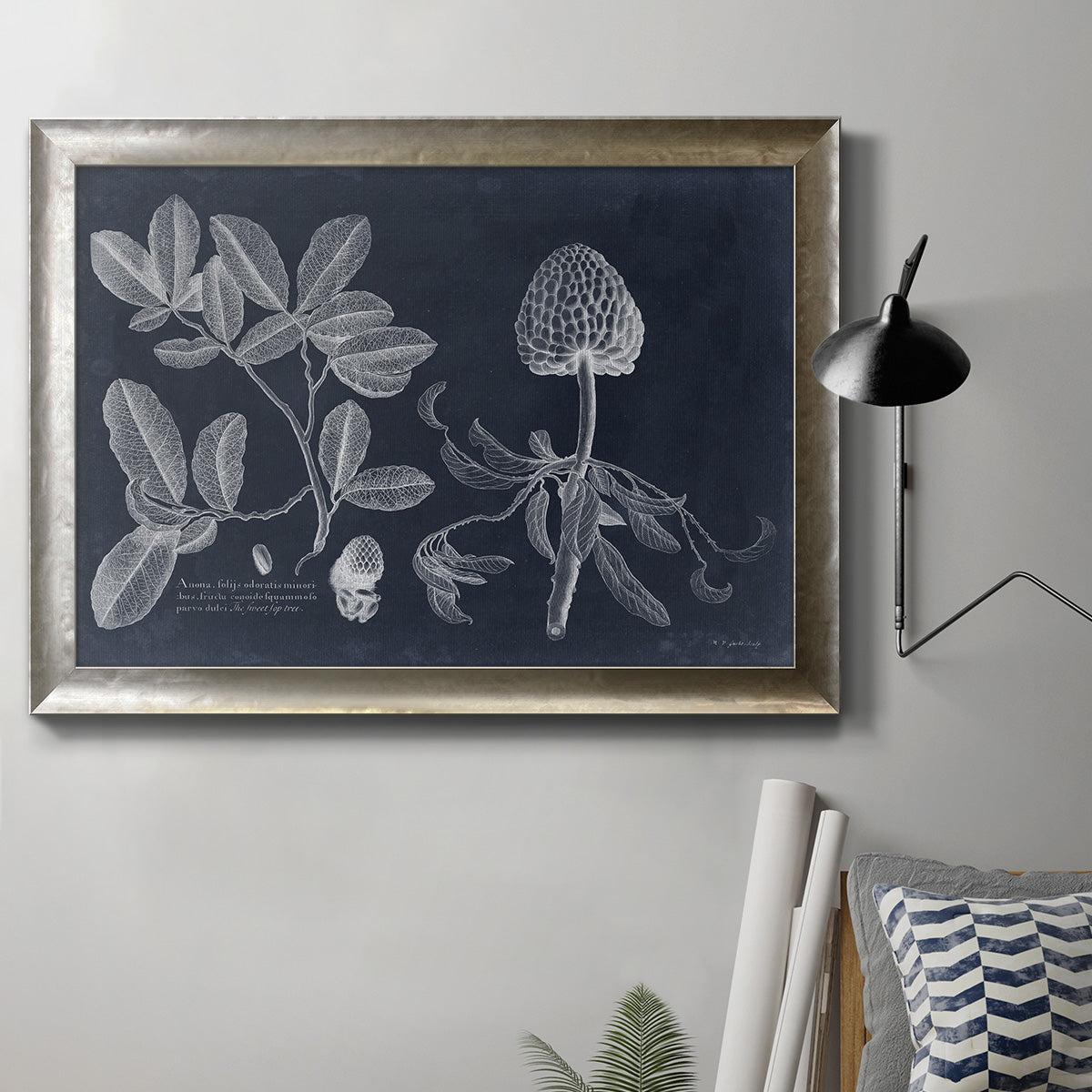 Antique botanical foliage illustration on navy background in an ornate mottled silver frame displayed in a neutral interior setting.