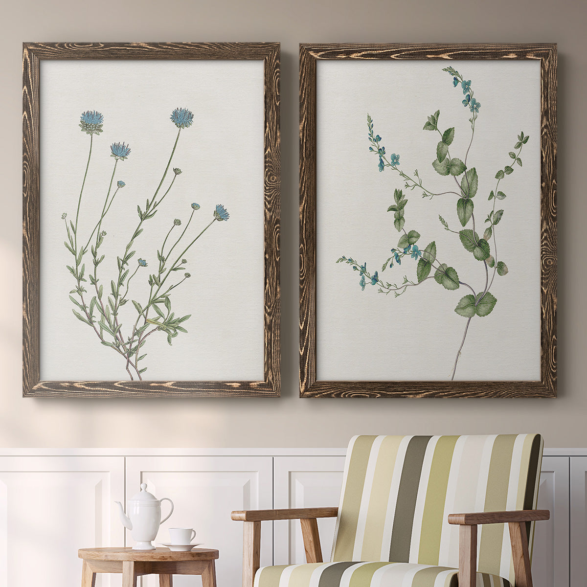 Set of two walnut barnwood framed canvas prints depicting two rustic minimalist botanical studies featuring delicate wildflower and leafy stems above a sideboard in a cozy sitting room.