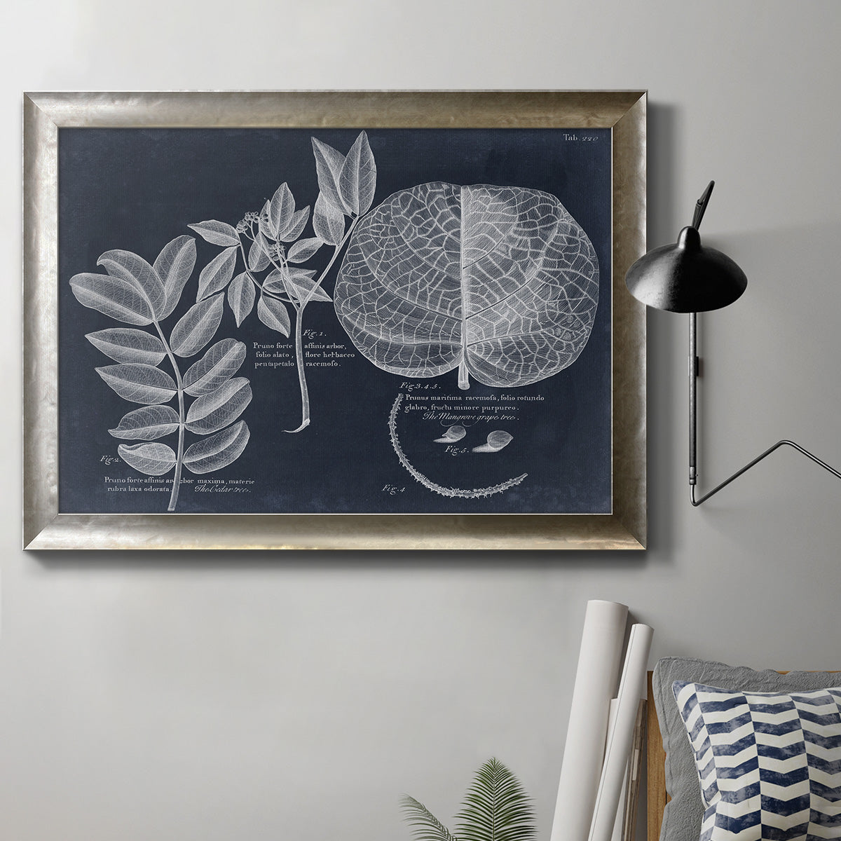 Vintage botanical foliage illustration on navy background in an ornate mottled silver frame displayed in a neutral interior setting.
