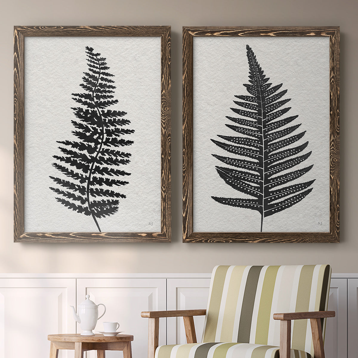 Set of two walnut barnwood framed canvas prints depicting two minimalist botanical prints featuring black fern leaf silhouettes above a sideboard in a cozy sitting room.