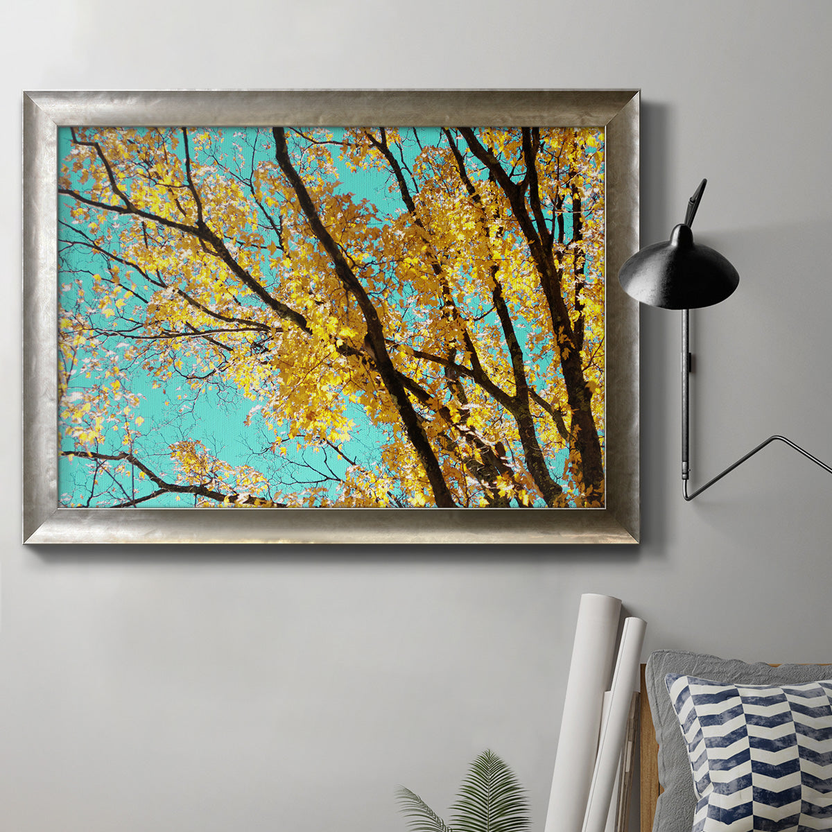 Bright autumn leaves against a blue sky in an ornate mottled silver frame displayed in a neutral interior setting.