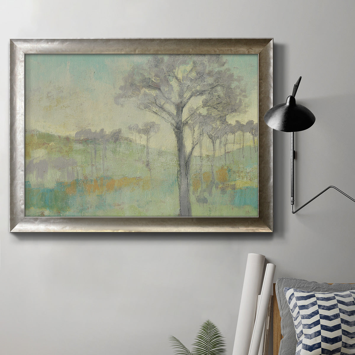 Classical watercolor landscape with trees in an ornate mottled silver frame displayed in a neutral interior setting.