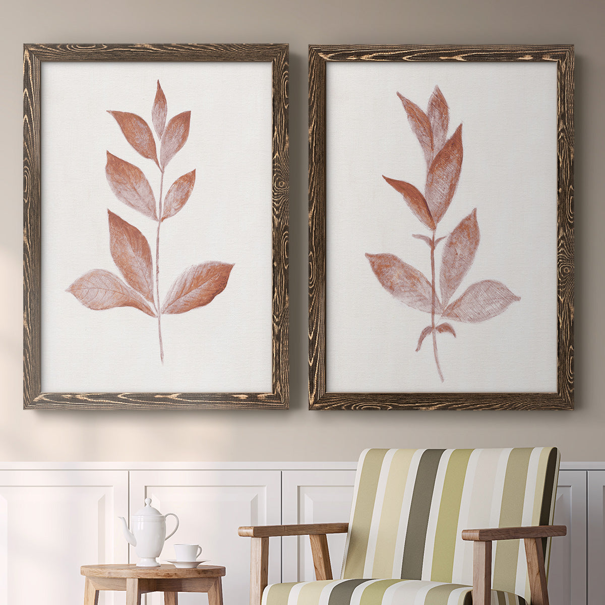 Set of two walnut barnwood framed canvas prints depicting two minimalist botanical prints featuring single rust-red leafy stems above a sideboard in a cozy sitting room.