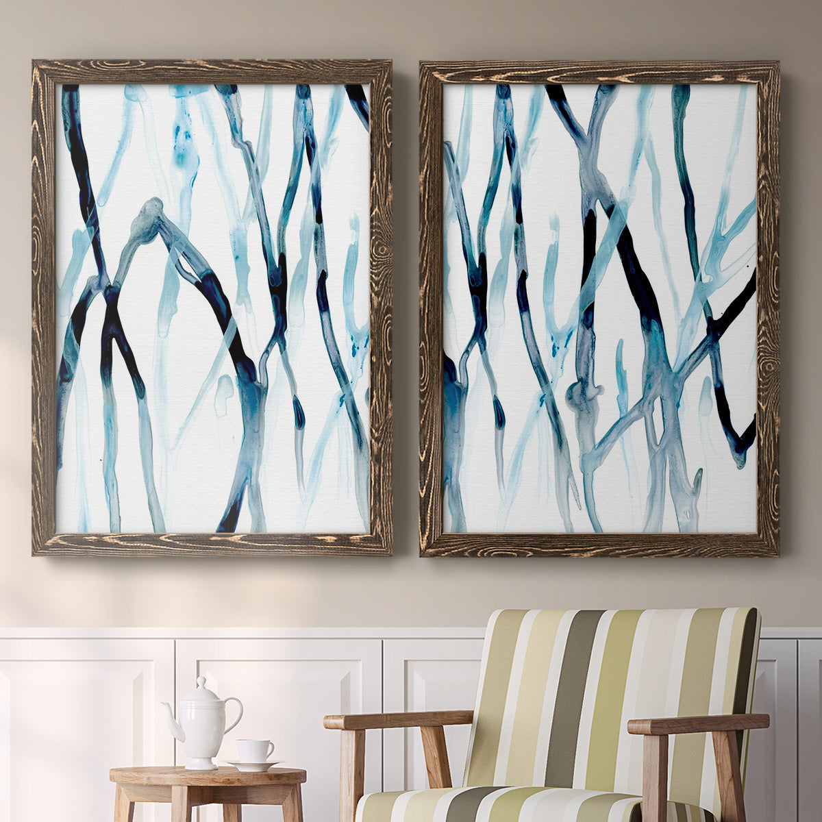 Set of two walnut barnwood framed canvas prints depicting two fluid organic abstracts featuring branching watercolor lines drifting across white above a sideboard in a cozy sitting room.