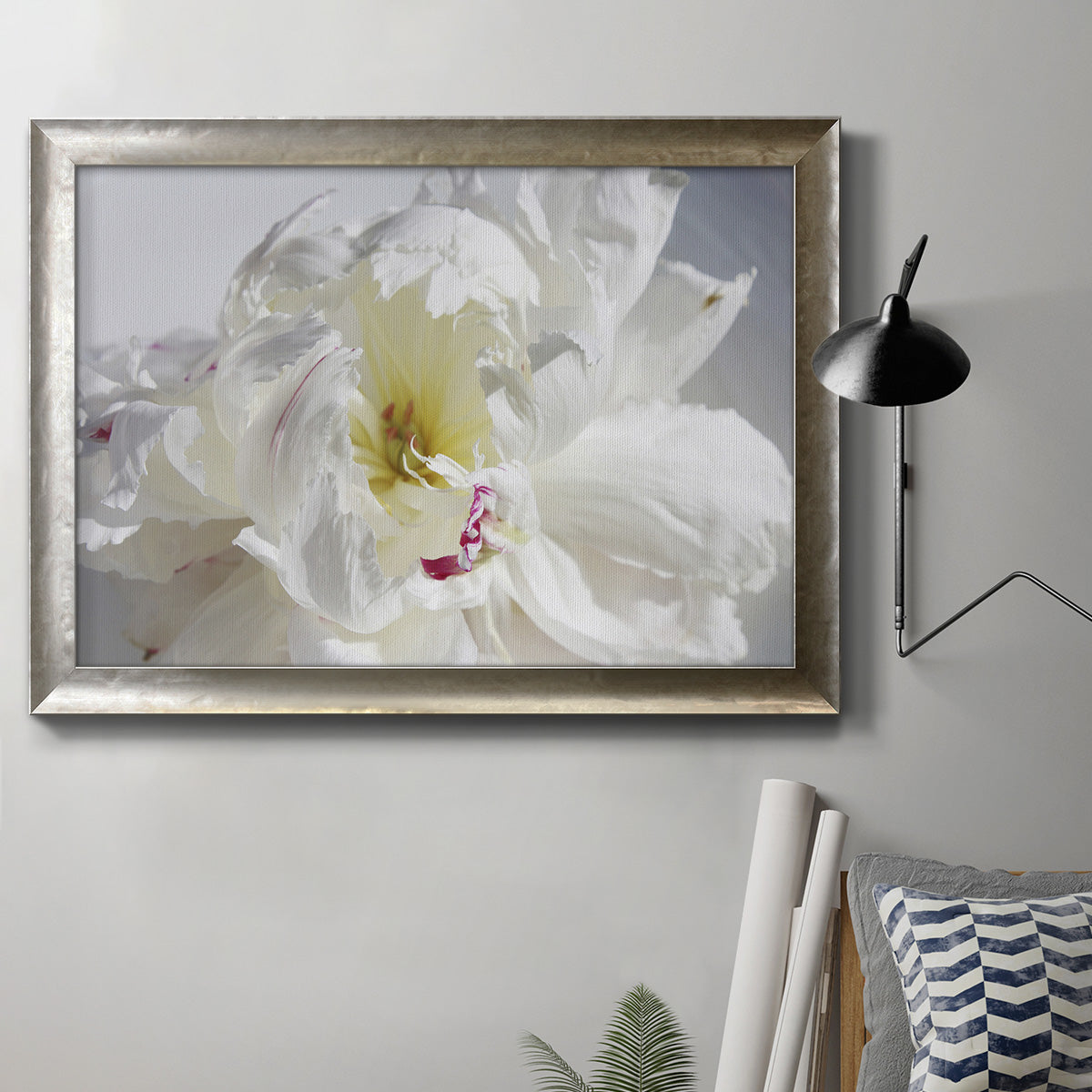 Soft white peony close-up in an ornate mottled silver frame displayed in a neutral interior setting.
