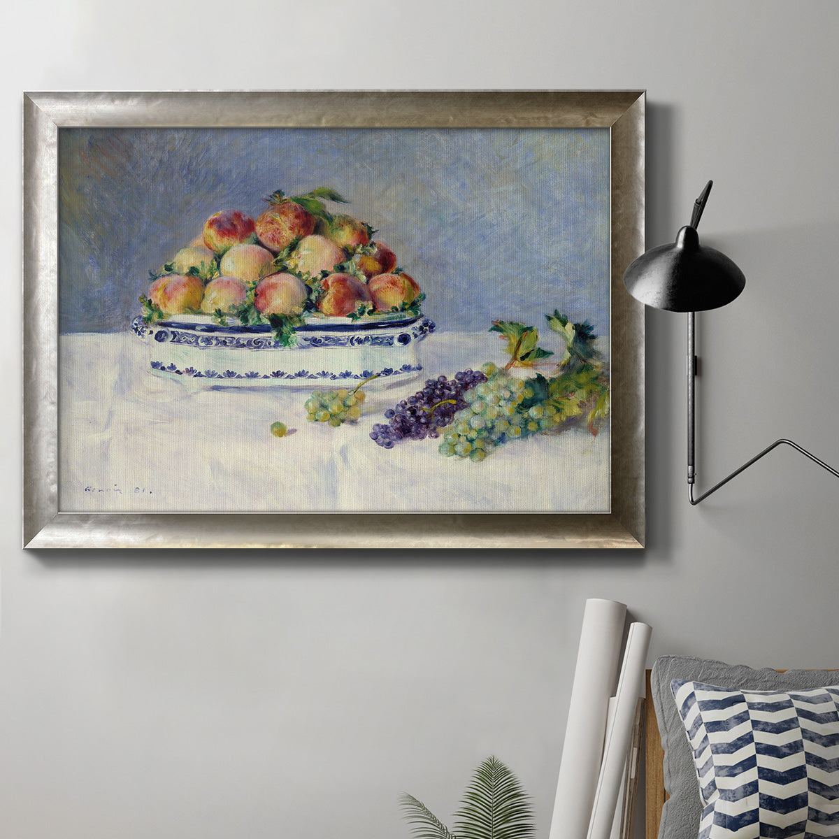 Impressionist still life painting with peaches and grapes in an ornate mottled silver frame displayed in a neutral interior setting.