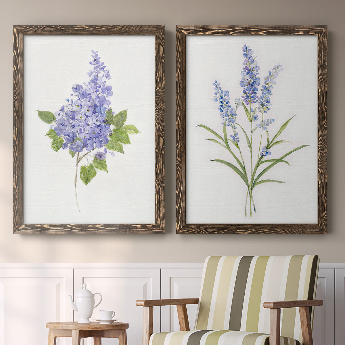 Set of two walnut barnwood framed canvas prints depicting two delicate watercolor botanical studies featuring purple lilac and blue wildflower stems above a sideboard in a cozy sitting room.