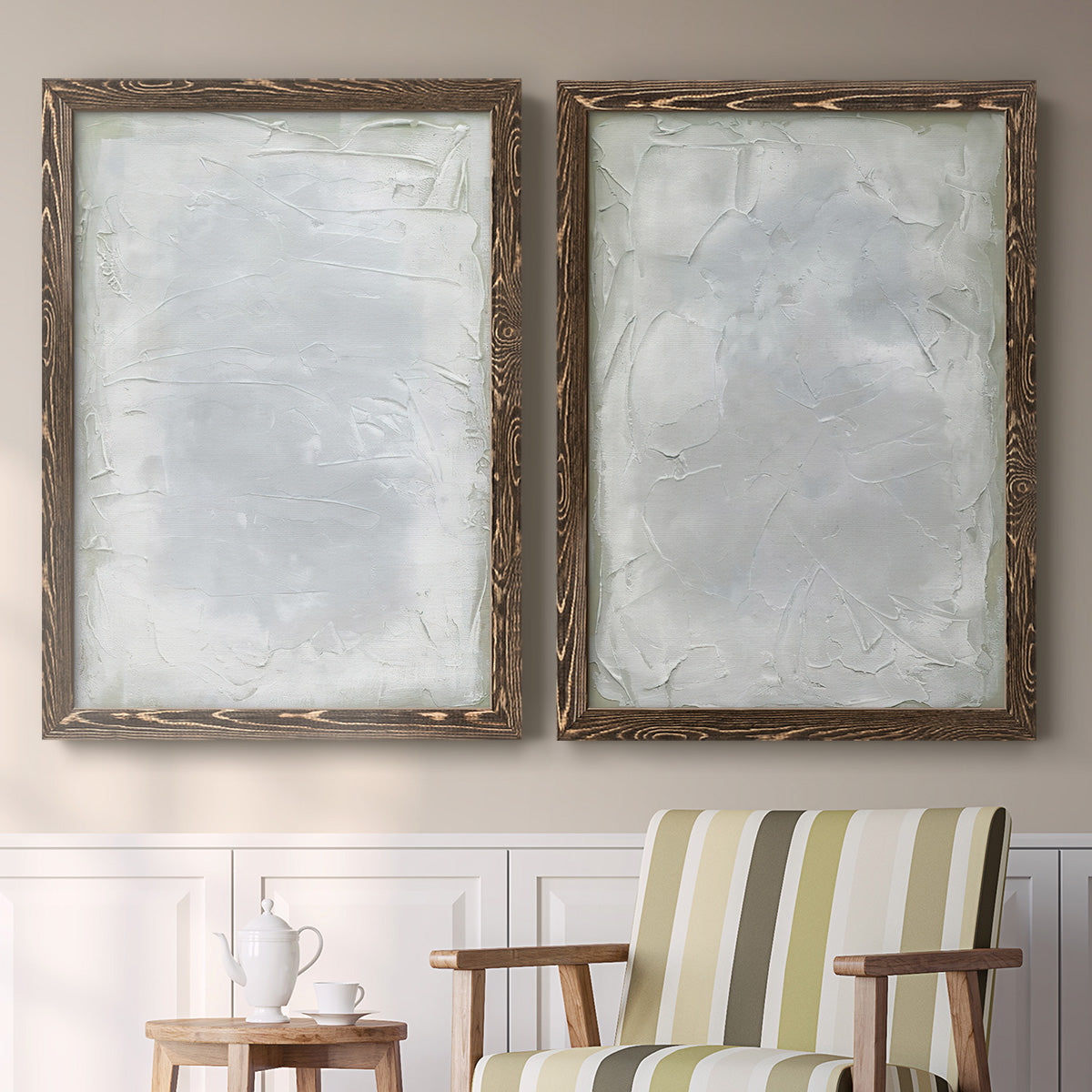 Set of two walnut barnwood framed canvas prints depicting two quiet textural abstracts featuring layered white and silver-gray painted surfaces above a sideboard in a cozy sitting room.