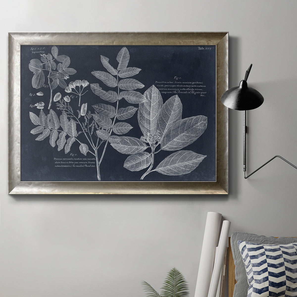 Antique botanical foliage artwork on navy background in an ornate mottled silver frame displayed in a neutral interior setting.