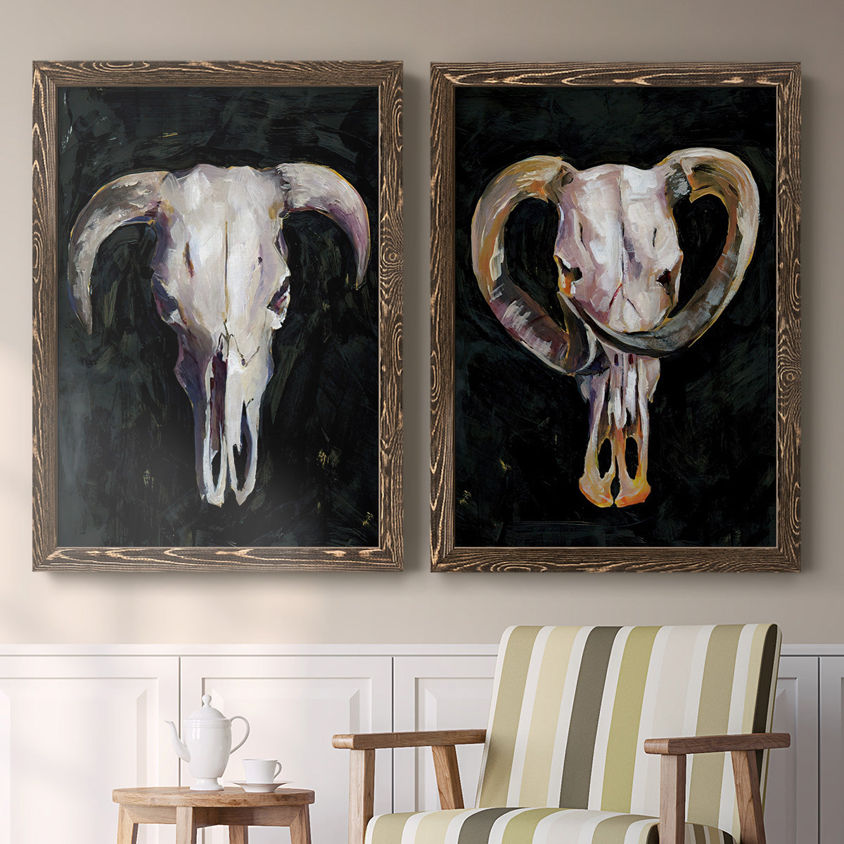 Set of two walnut barnwood framed canvas prints depicting two dramatic Western animal paintings featuring ram and cattle skulls against black grounds above a sideboard in a cozy sitting room.