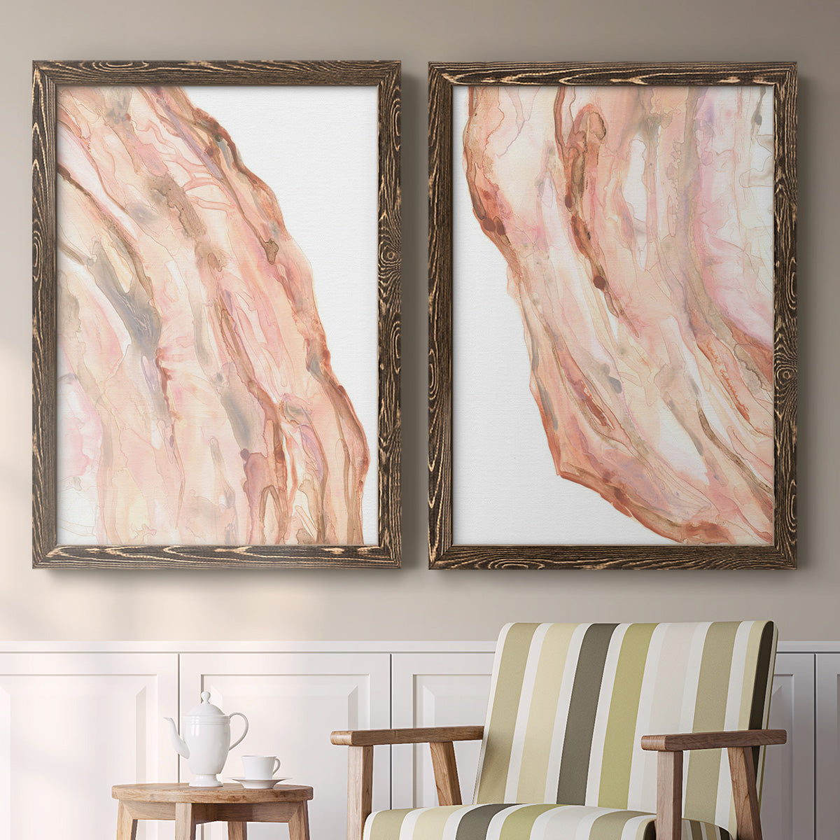 Set of two walnut barnwood framed canvas prints depicting two soft marble-inspired abstracts featuring flowing blush peach and cream mineral bands above a sideboard in a cozy sitting room.