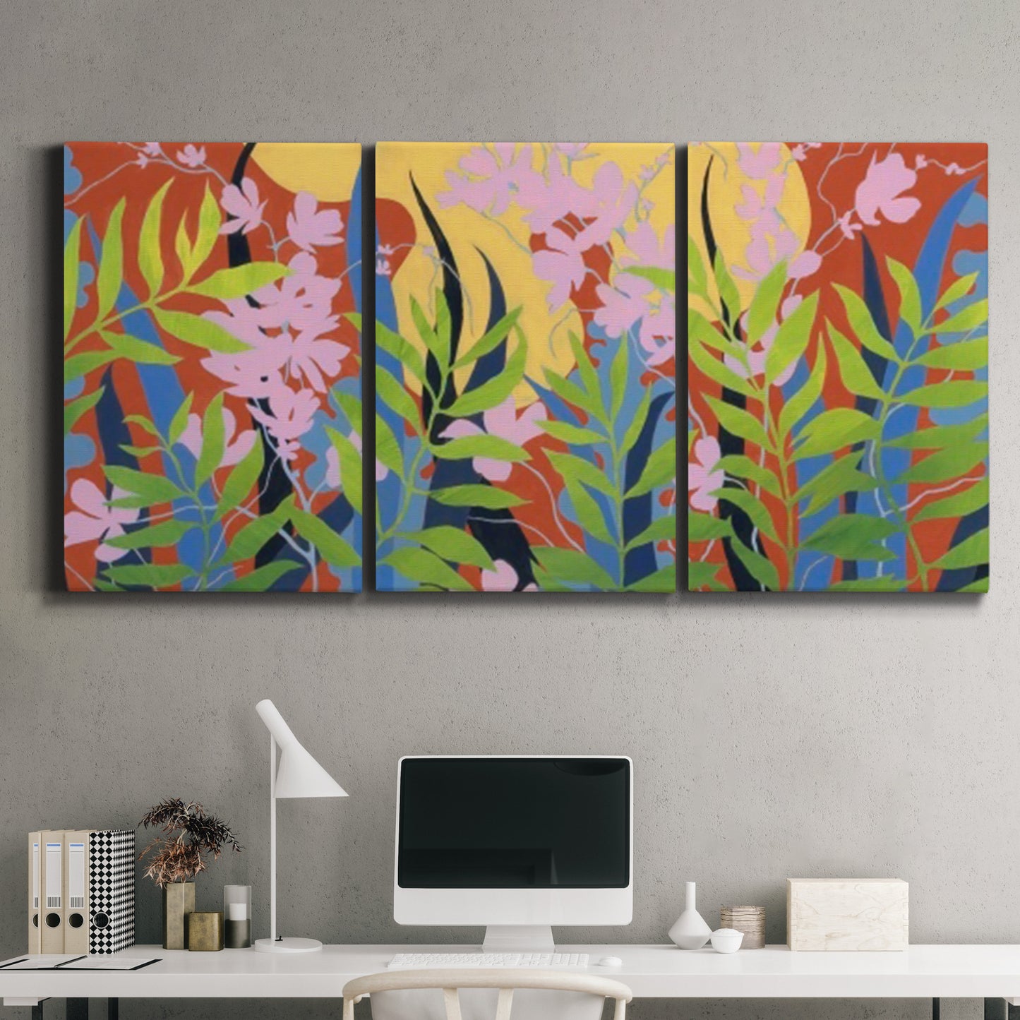 Three-panel canvas wall art featuring bold colorful floral abstraction, displayed above a desk in a home office.