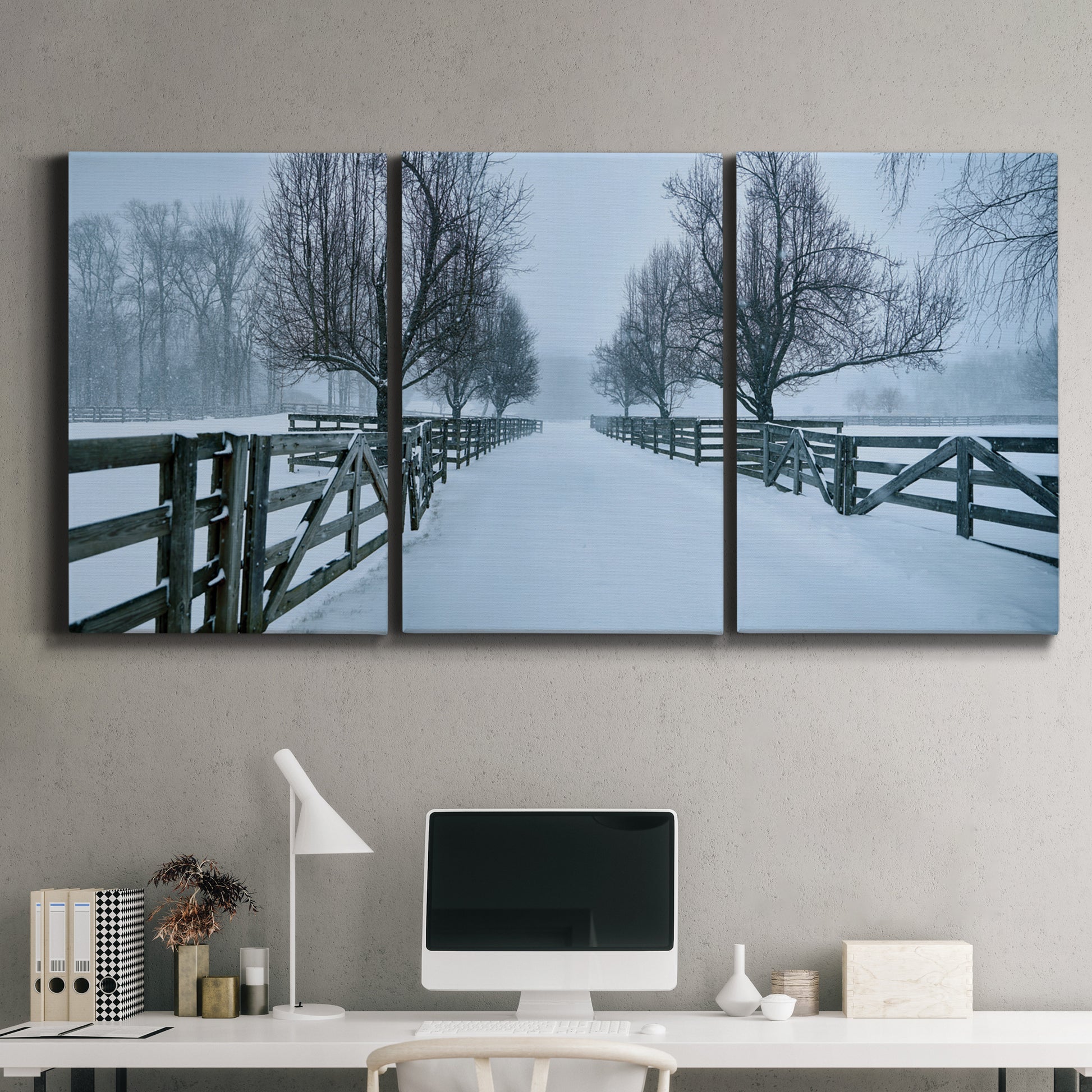 Three-panel canvas wall art featuring snow covered rural road photograph, displayed above a desk in a home office.