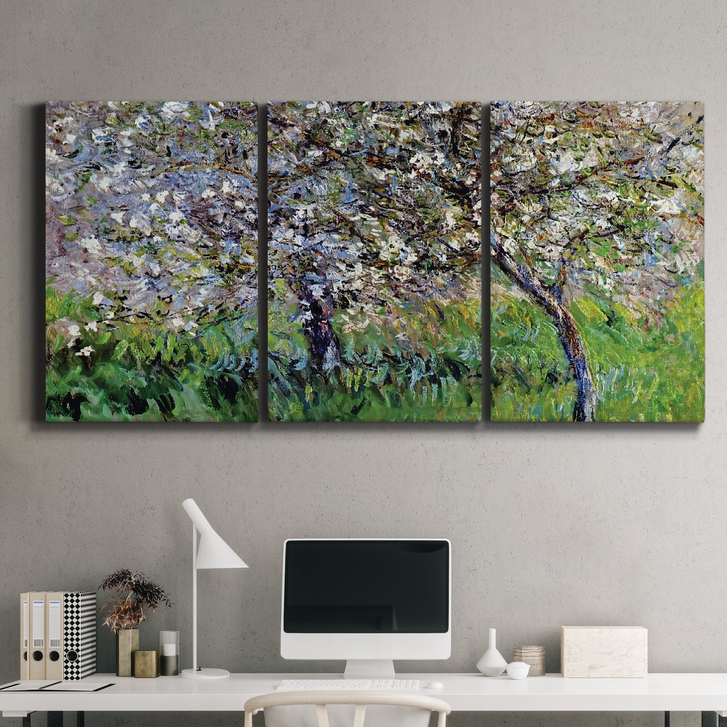 Three-panel canvas wall art featuring apple trees blooming beside water, displayed above a desk in a home office.