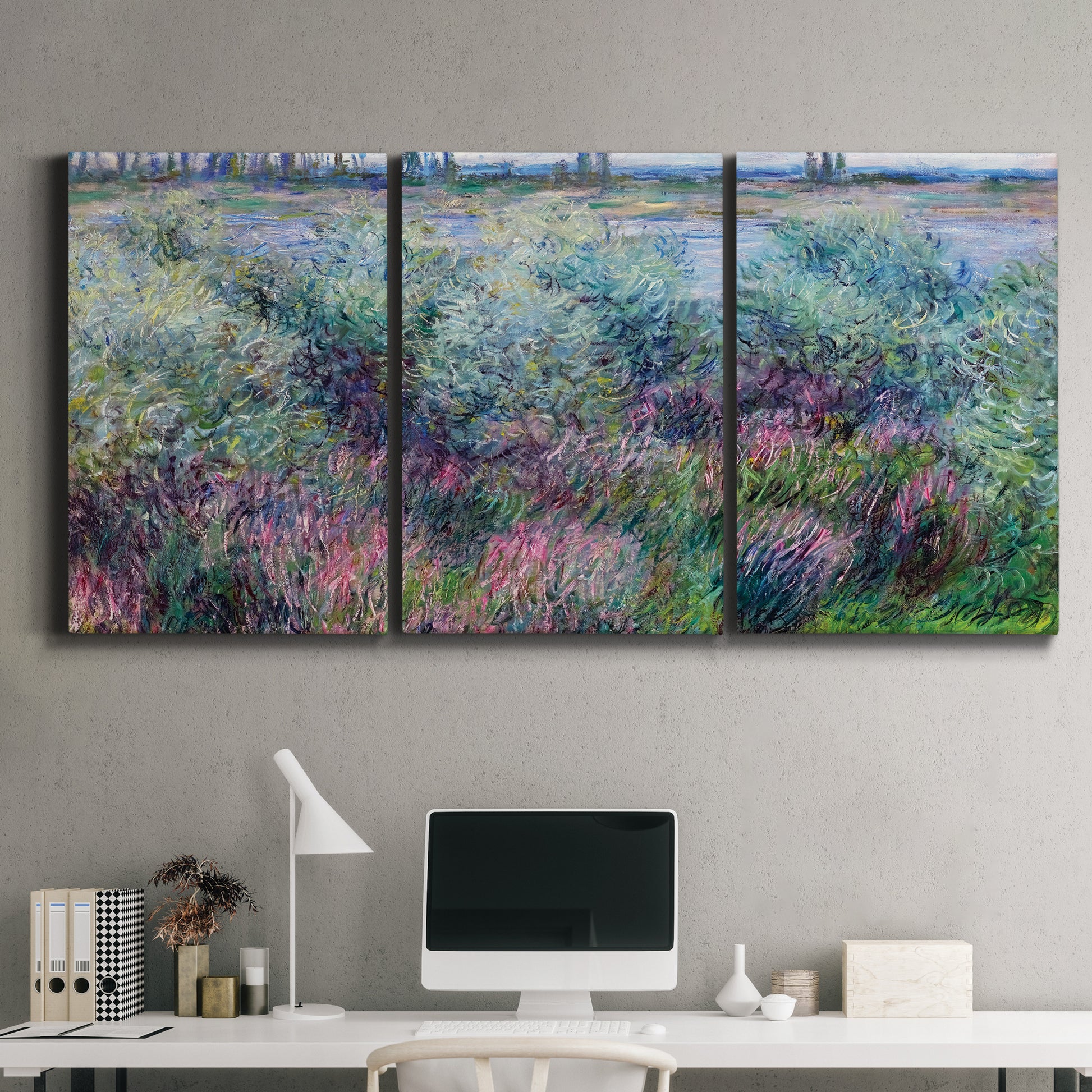 Three-panel canvas wall art featuring flowered riverbank with trees, displayed above a desk in a home office.