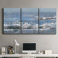 Three-panel canvas wall art featuring overcast coastal waves under grey sky, displayed above a desk in a home office.