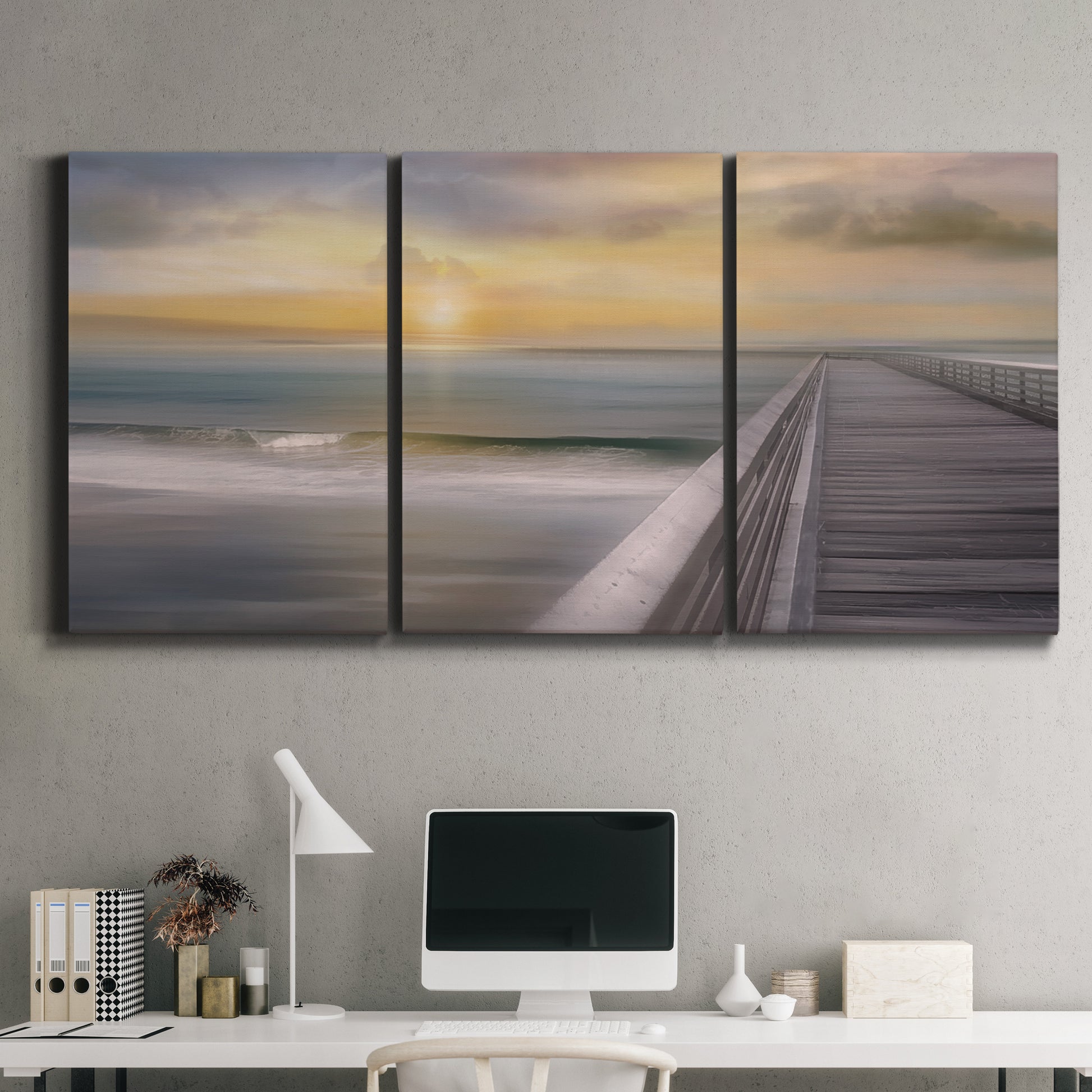 Three-panel canvas wall art featuring tropical beach at sunset photograph, displayed above a desk in a home office.