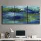 Three-panel canvas wall art featuring flowing blue abstract watercolor, displayed above a desk in a home office.