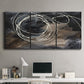 Three-panel canvas wall art featuring dark swirling abstract motion, displayed above a desk in a home office.