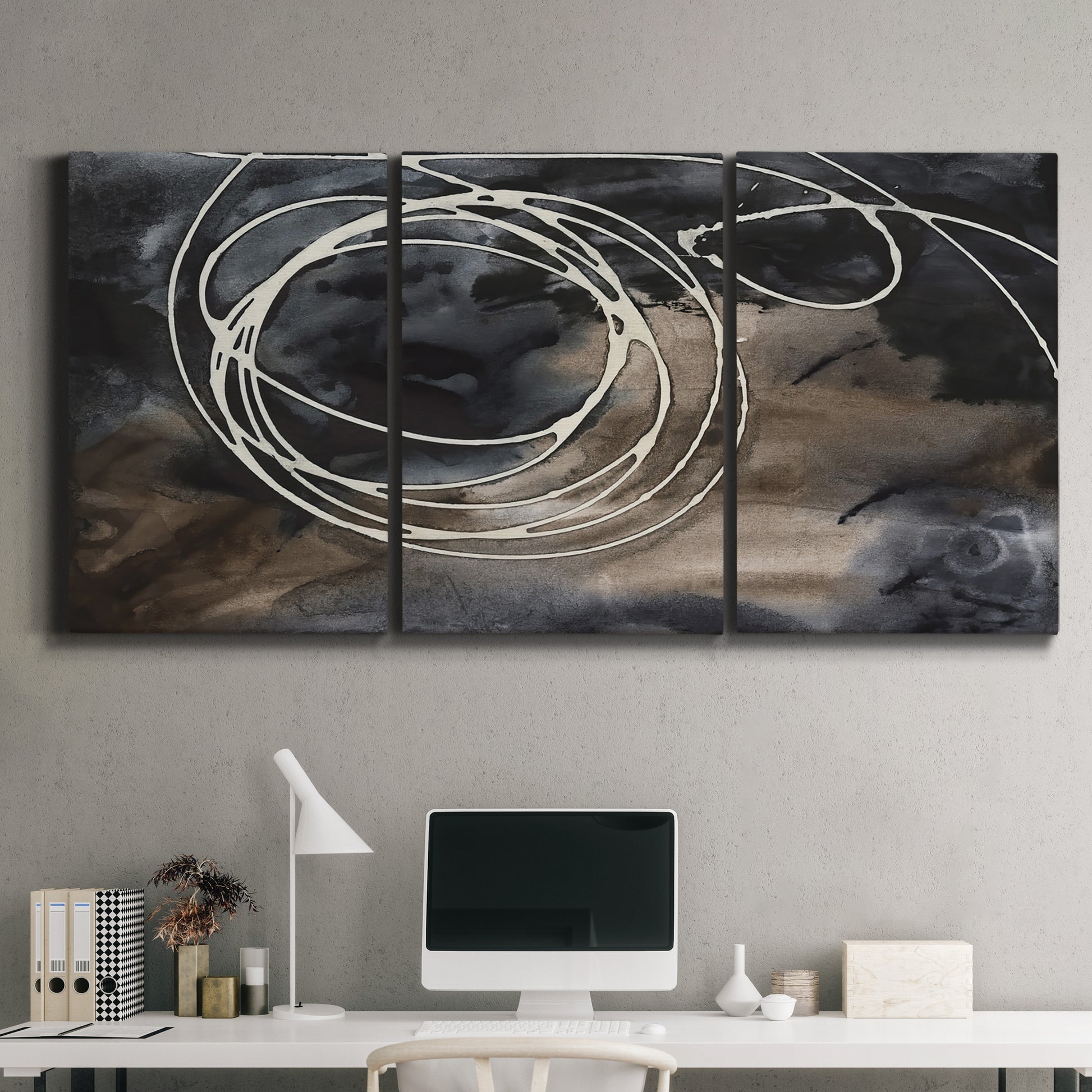Three-panel canvas wall art featuring dark swirling abstract motion, displayed above a desk in a home office.