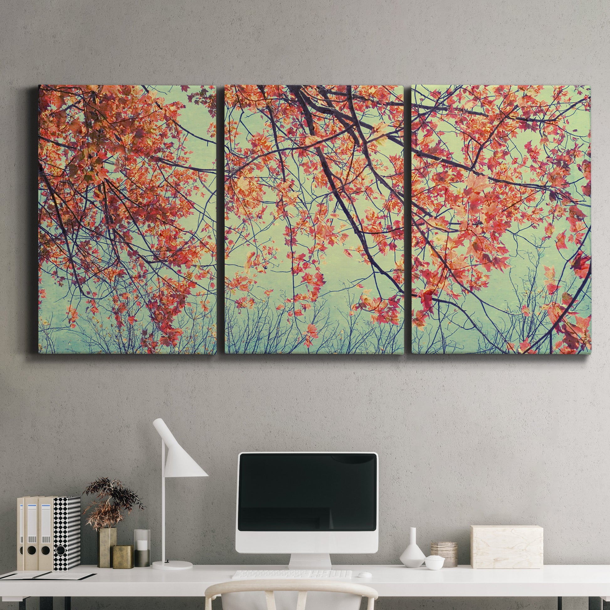 Three-panel canvas wall art featuring autumn foliage landscape photograph, displayed above a desk in a home office.