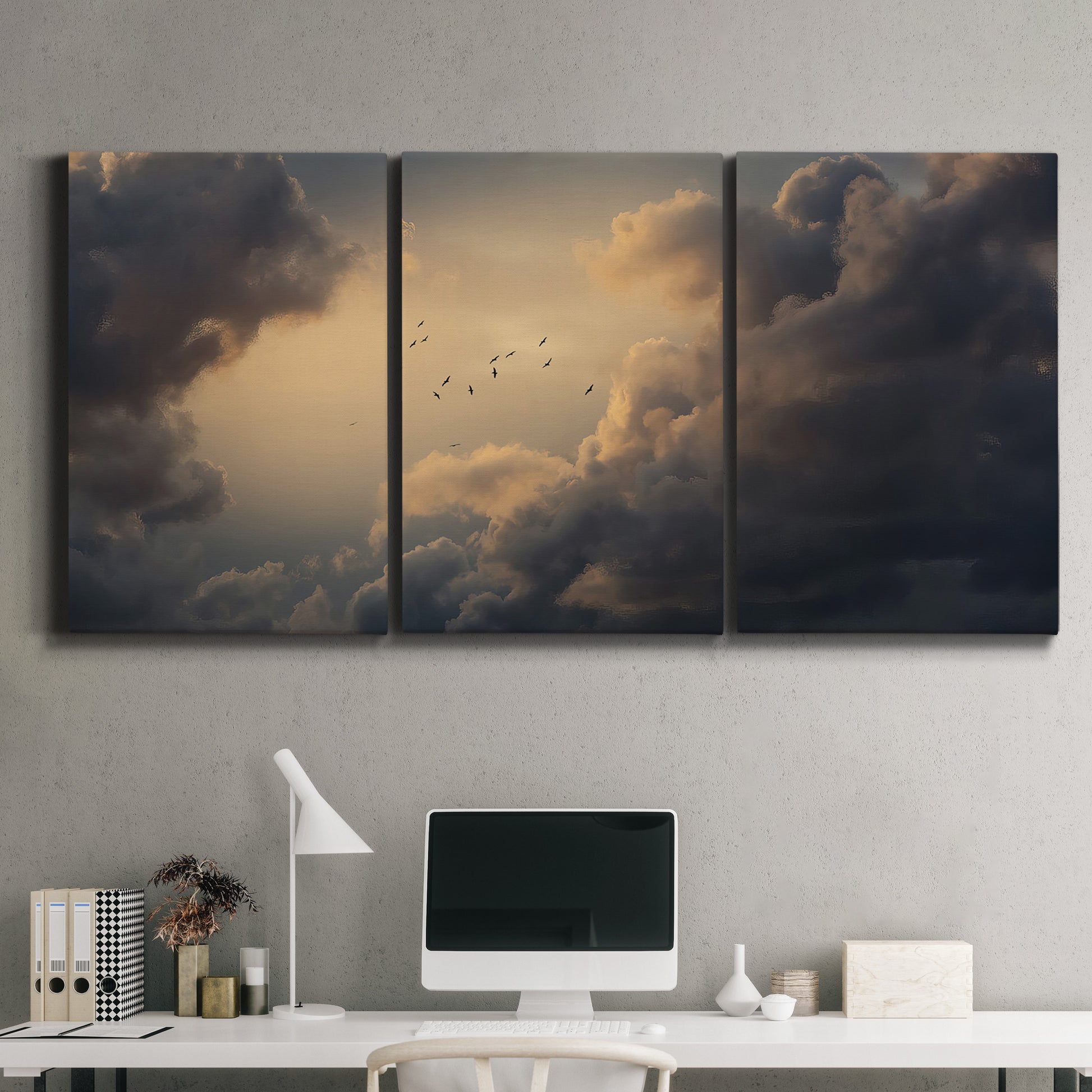 Three-panel canvas wall art featuring surreal floating figures above landscape, displayed above a desk in a home office.