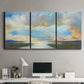 Three-panel canvas wall art featuring dawn light breaking over water, displayed above a desk in a home office.