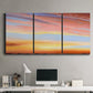 Three-panel canvas wall art featuring glowing sunset sky over landscape, displayed above a desk in a home office.