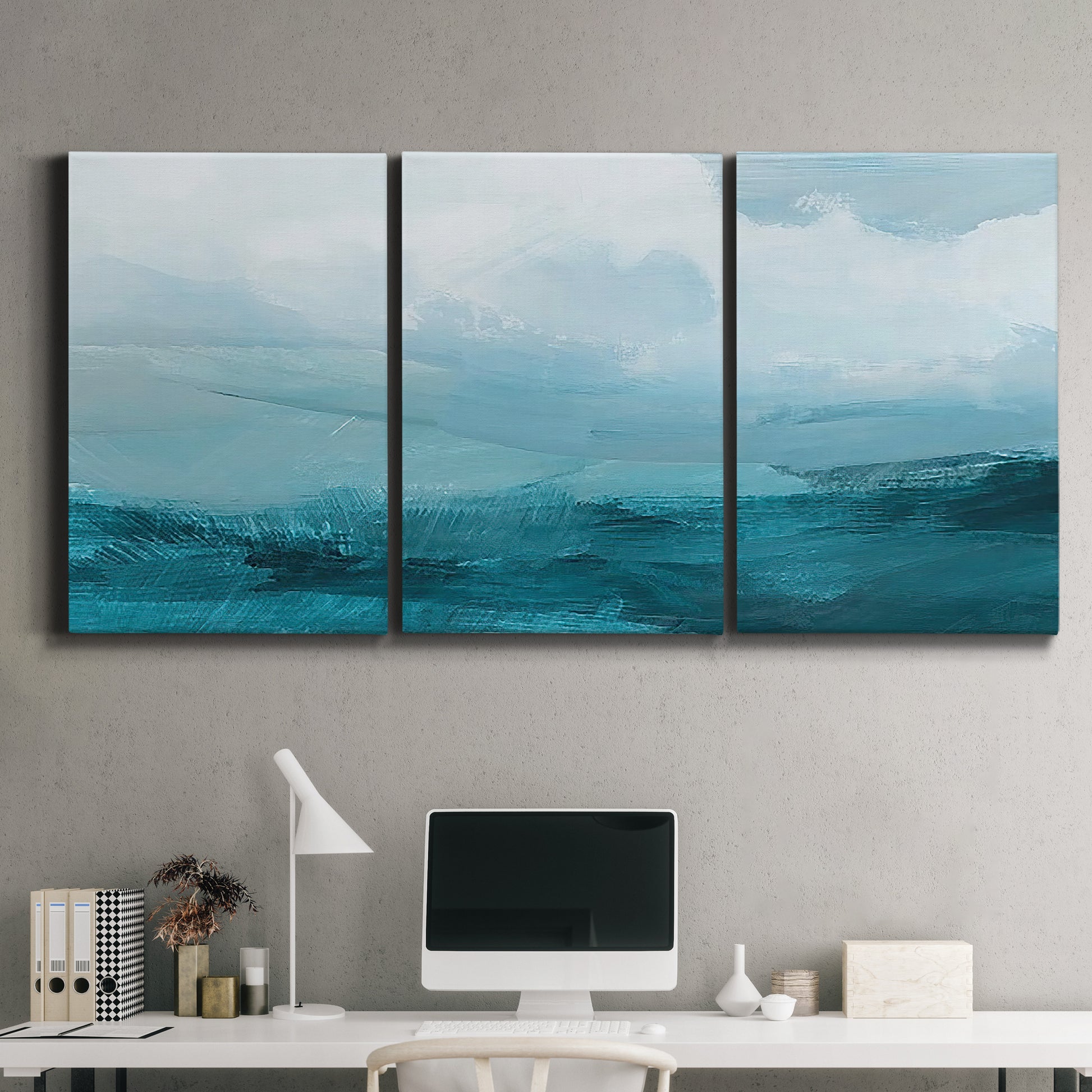 Three-panel canvas wall art featuring vertical coastal elements with rising light, displayed above a desk in a home office.