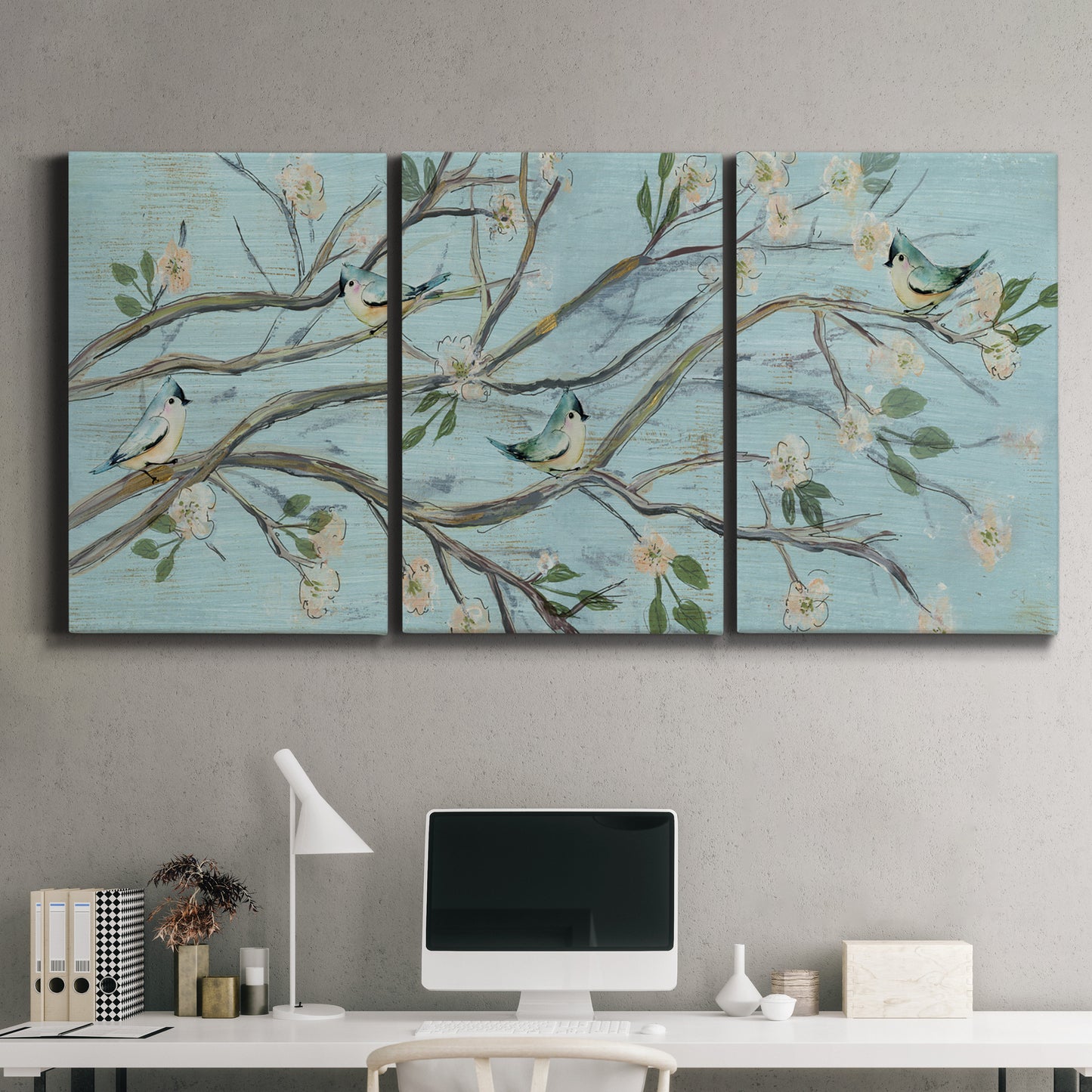 Three-panel canvas wall art featuring blue sky with flowering branches, displayed above a desk in a home office.