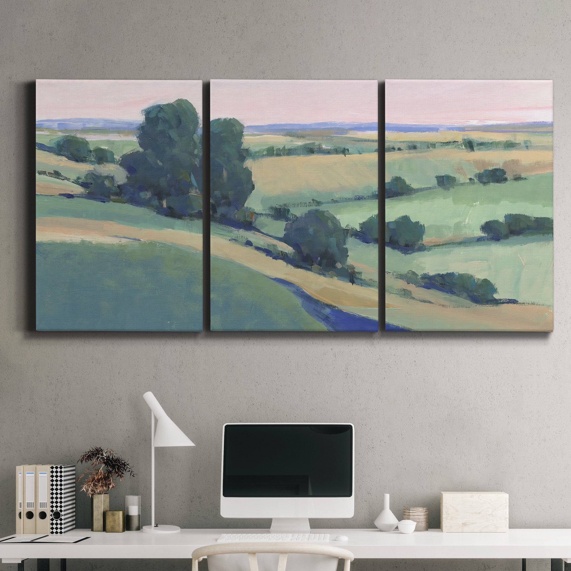 Three-panel canvas wall art featuring pastoral countryside with rocky outcrop, displayed above a desk in a home office.