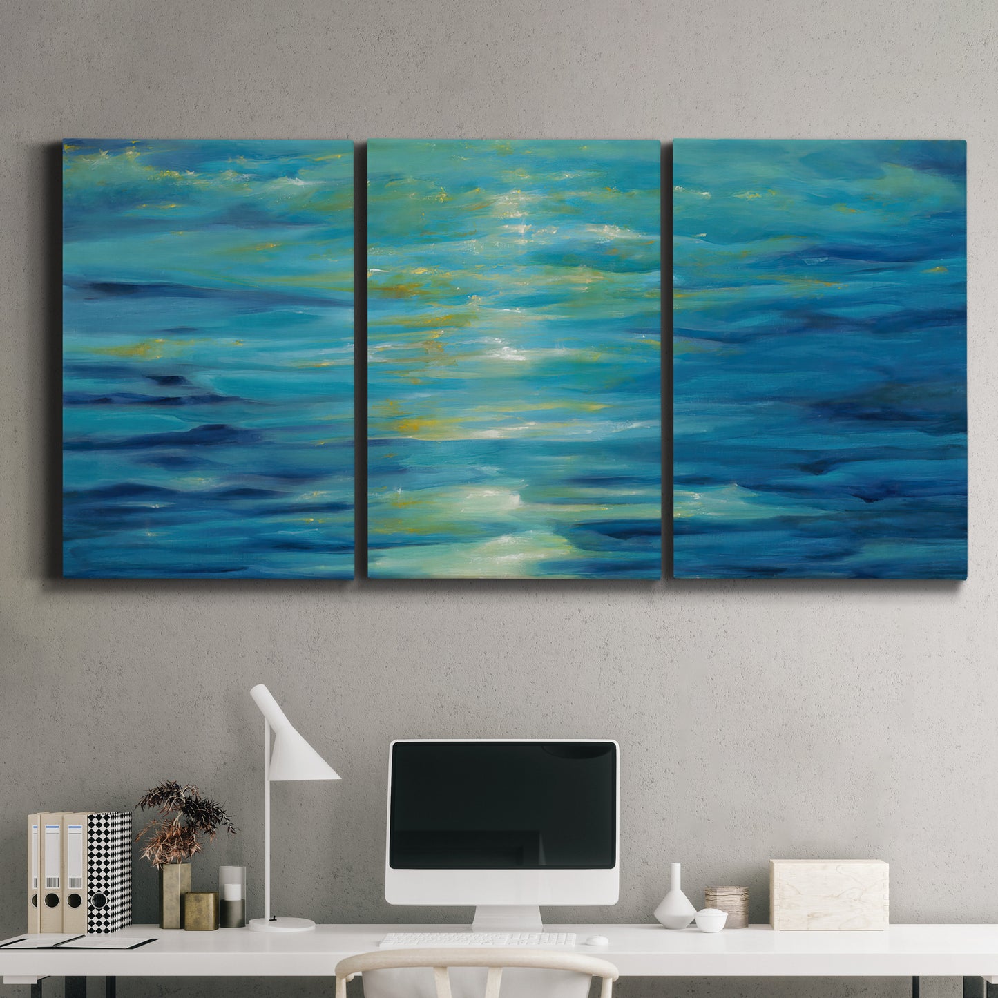 Three-panel canvas wall art featuring deep blue ocean water abstraction, displayed above a desk in a home office.