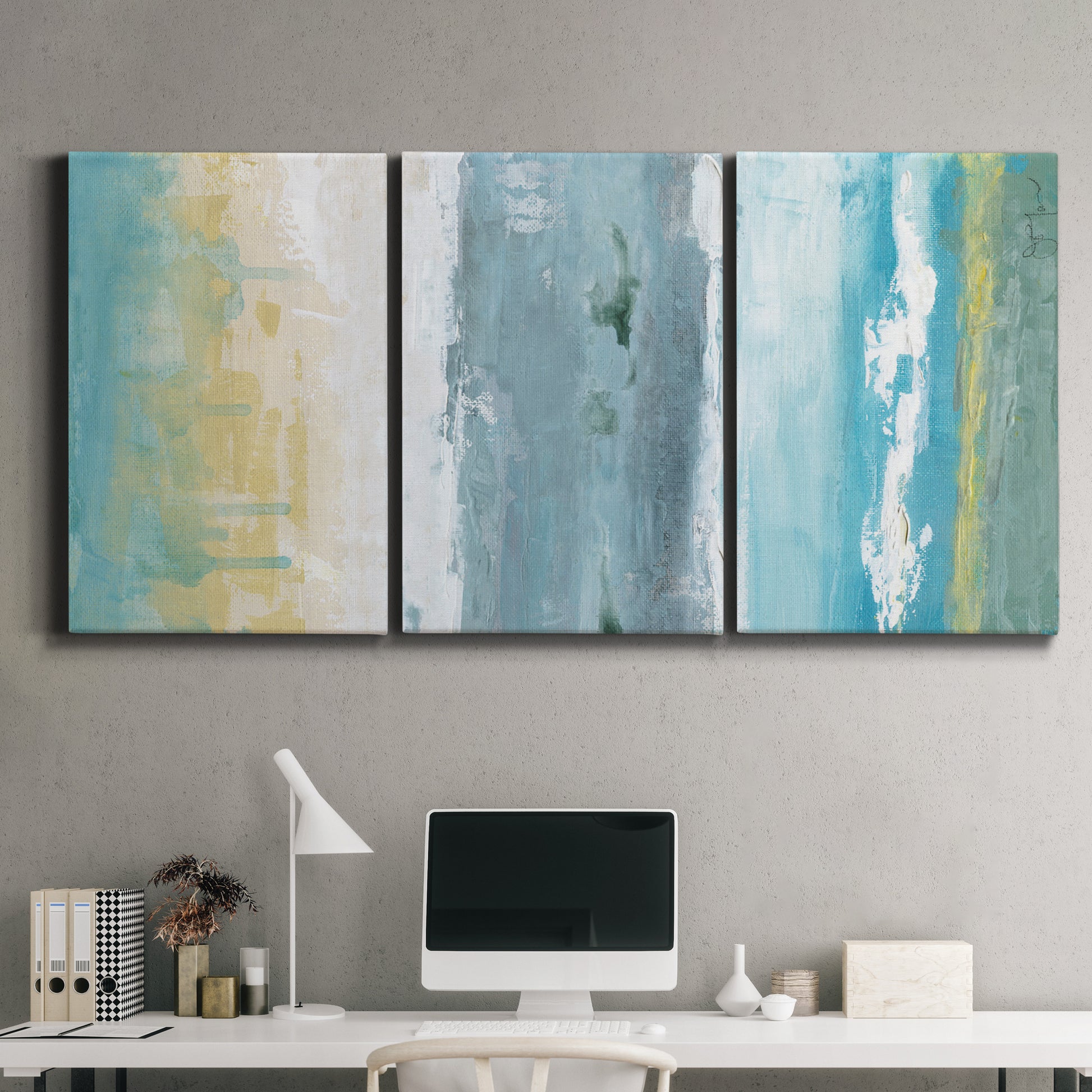 Three-panel canvas wall art featuring abstract coastal shoreline textures, displayed above a desk in a home office.