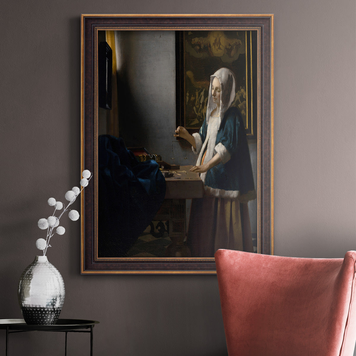 Quiet interior genre scene of a woman with scales by Johannes Vermeer in an ornate bronzed mahogany wood frame displayed in a neutral interior setting.
