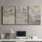 Three-panel canvas wall art featuring early spring blossoms in soft tones, displayed above a desk in a home office.