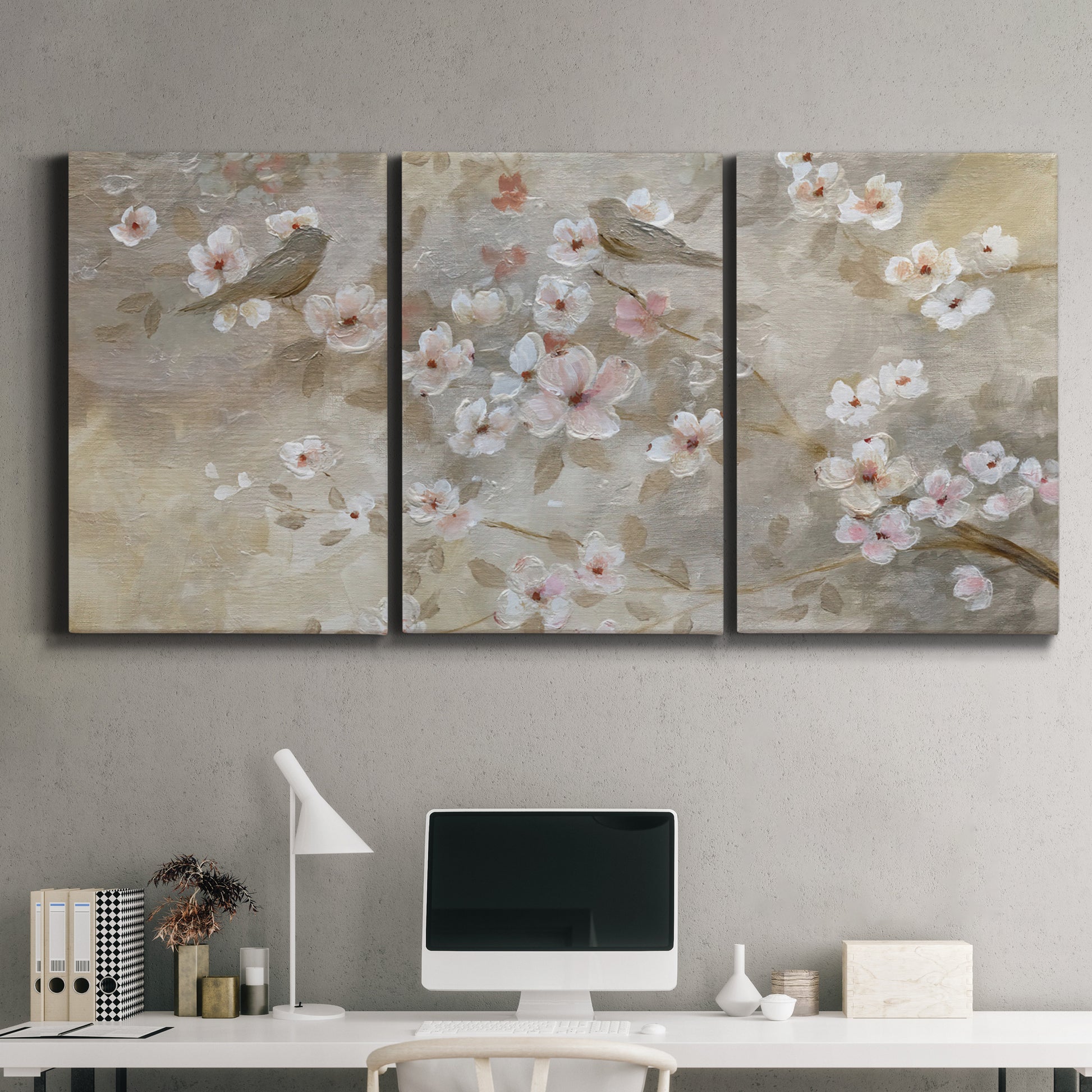 Three-panel canvas wall art featuring early spring blossoms in soft tones, displayed above a desk in a home office.