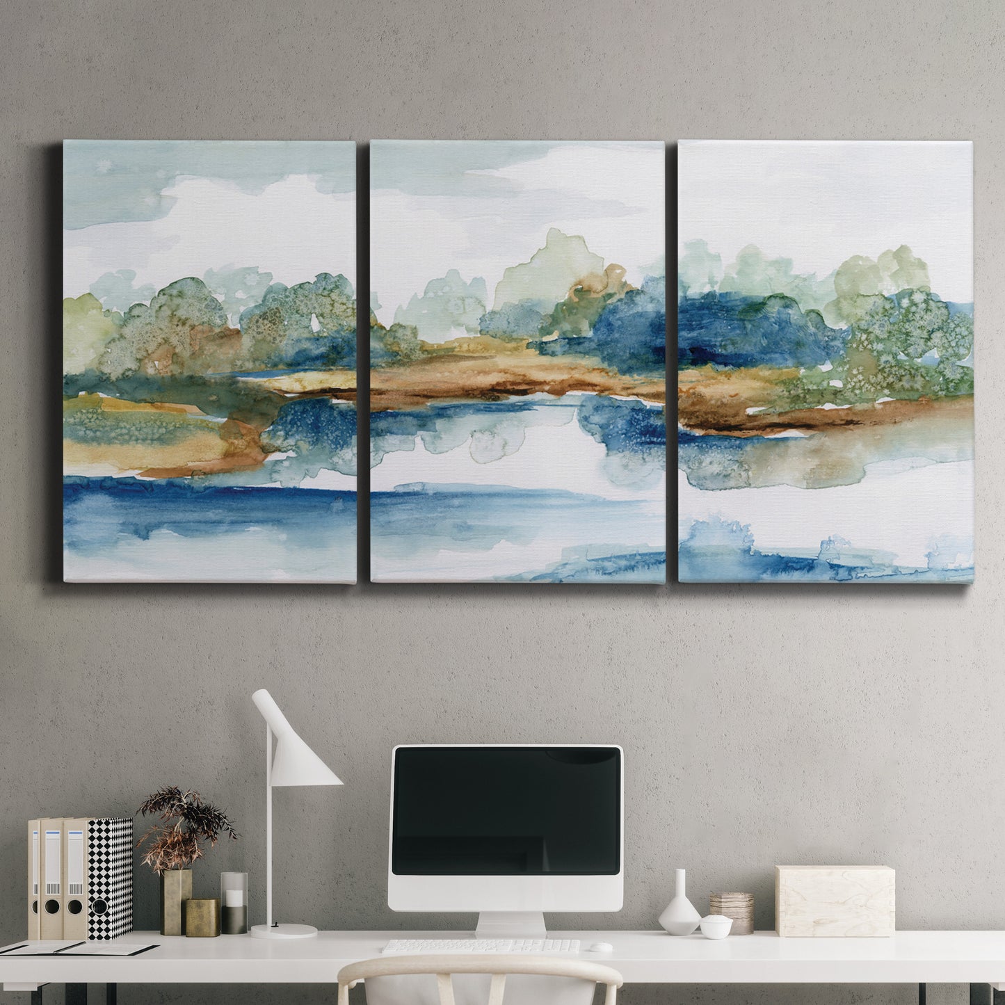 Three-panel canvas wall art featuring abstract blue watercolor landscape, displayed above a desk in a home office.