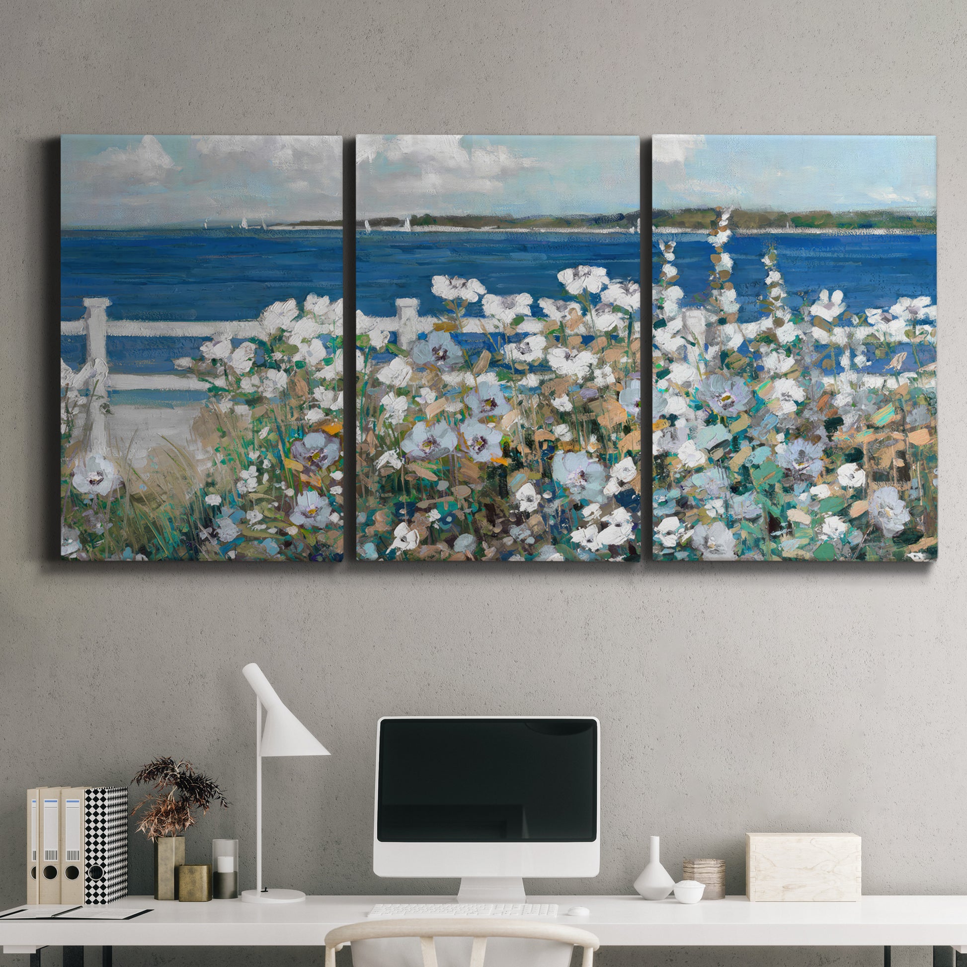 Three-panel canvas wall art featuring coastal garden overlooking bay, displayed above a desk in a home office.
