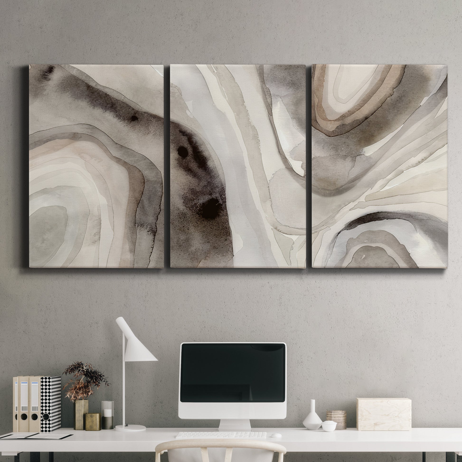 Three-panel canvas wall art featuring layered stone inspired abstract forms, displayed above a desk in a home office.