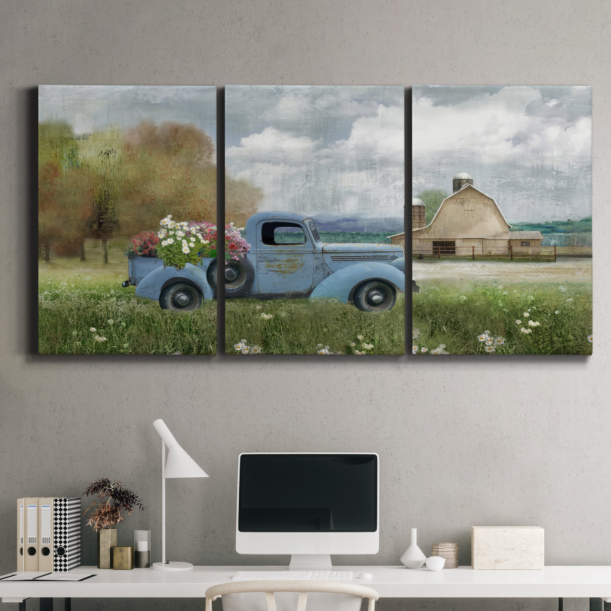 Three-panel canvas wall art featuring vintage blue truck with flower load, displayed above a desk in a home office.