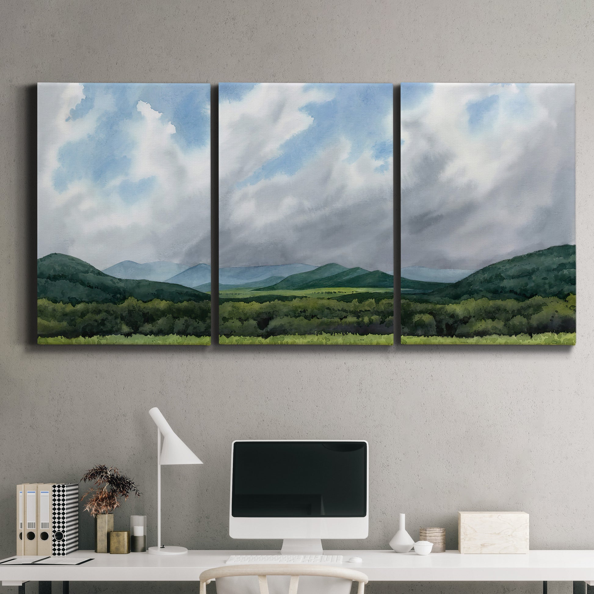 Three-panel canvas wall art featuring pastoral mountain landscape in blue, displayed above a desk in a home office.
