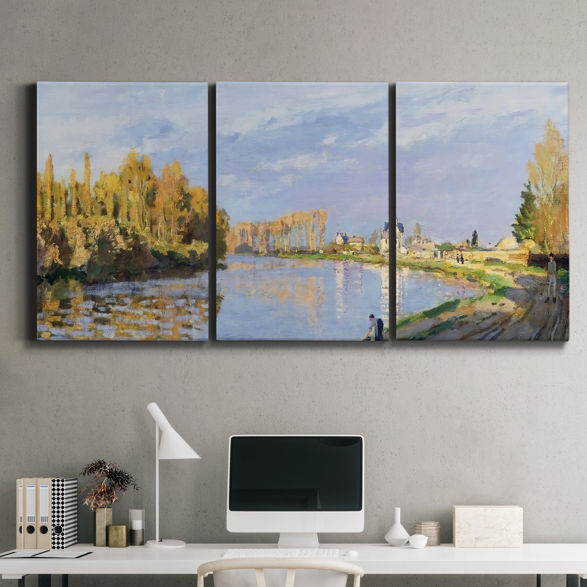 Three-panel canvas wall art featuring river flowing past village, displayed above a desk in a home office.