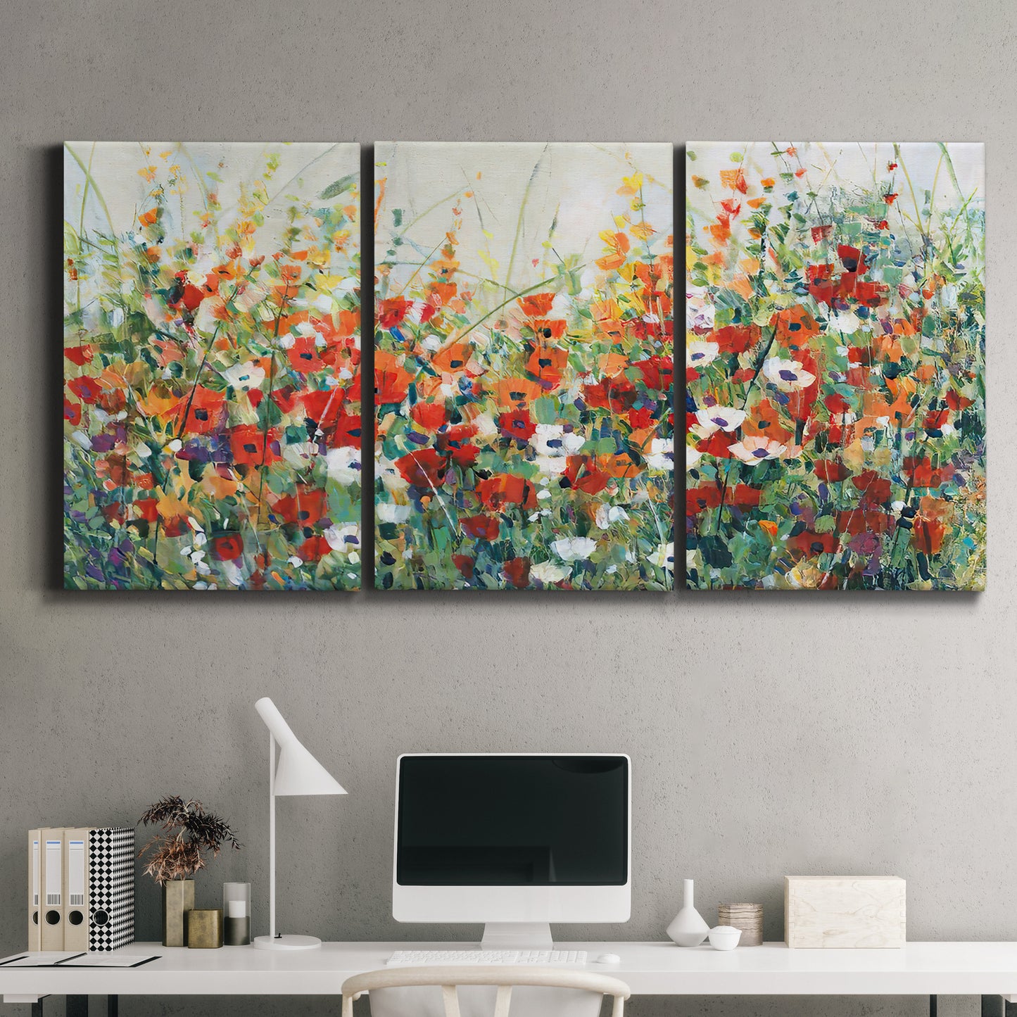 Three-panel canvas wall art featuring colorful garden flowers in bloom, displayed above a desk in a home office.