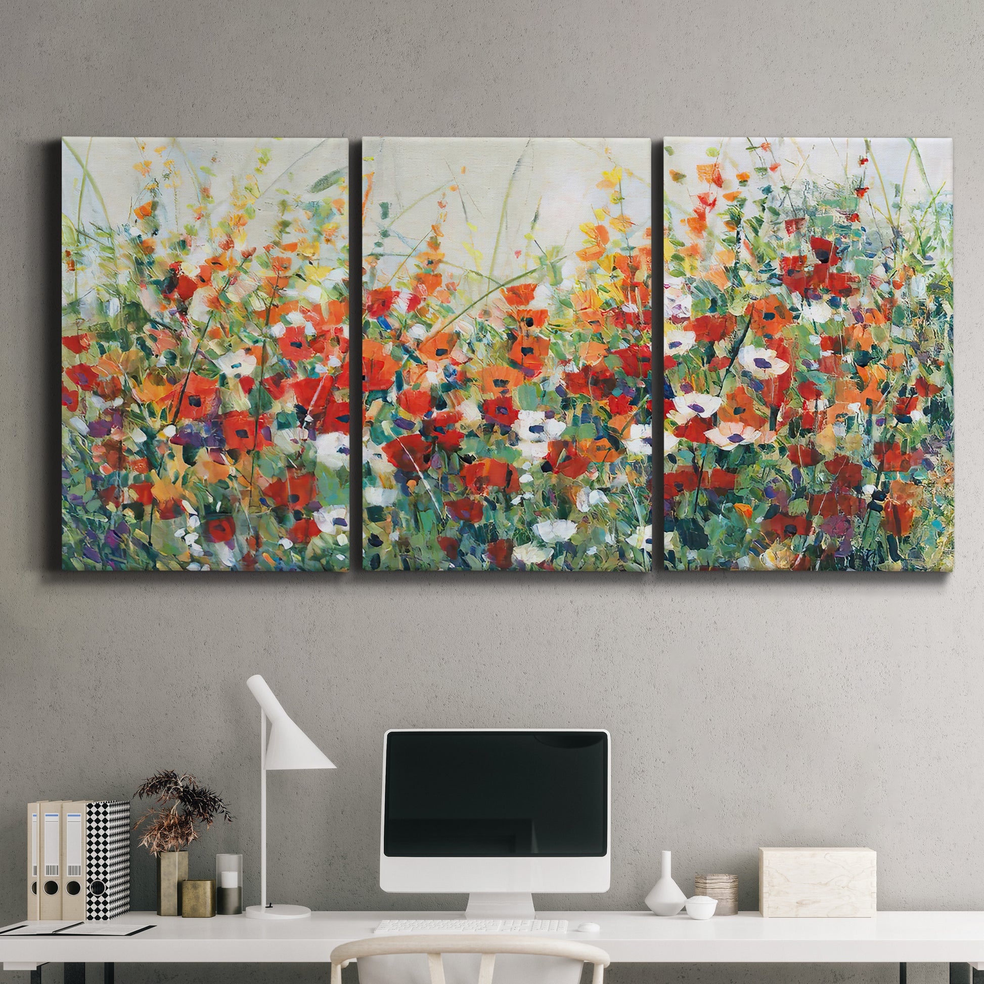 Three-panel canvas wall art featuring colorful garden flowers in bloom, displayed above a desk in a home office.