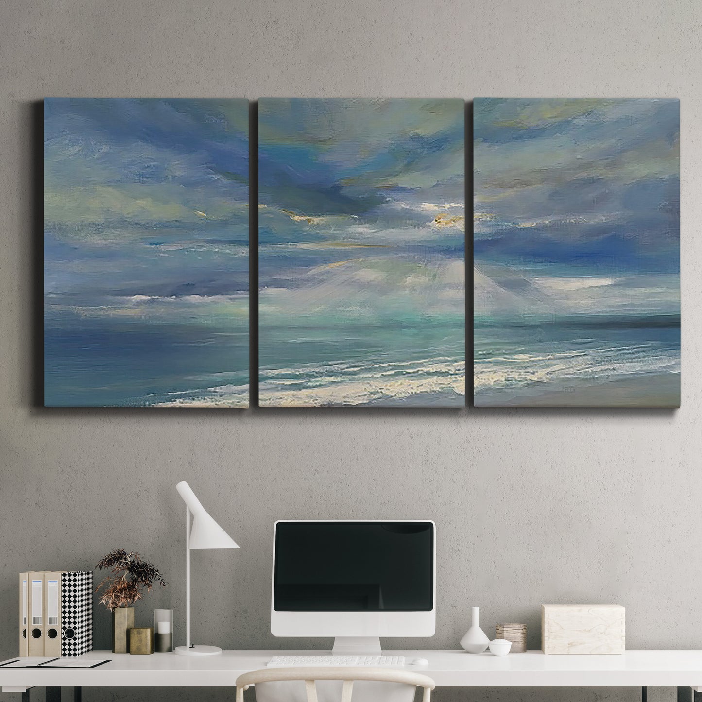 Three-panel canvas wall art featuring sunbeams breaking through coastal clouds, displayed above a desk in a home office.