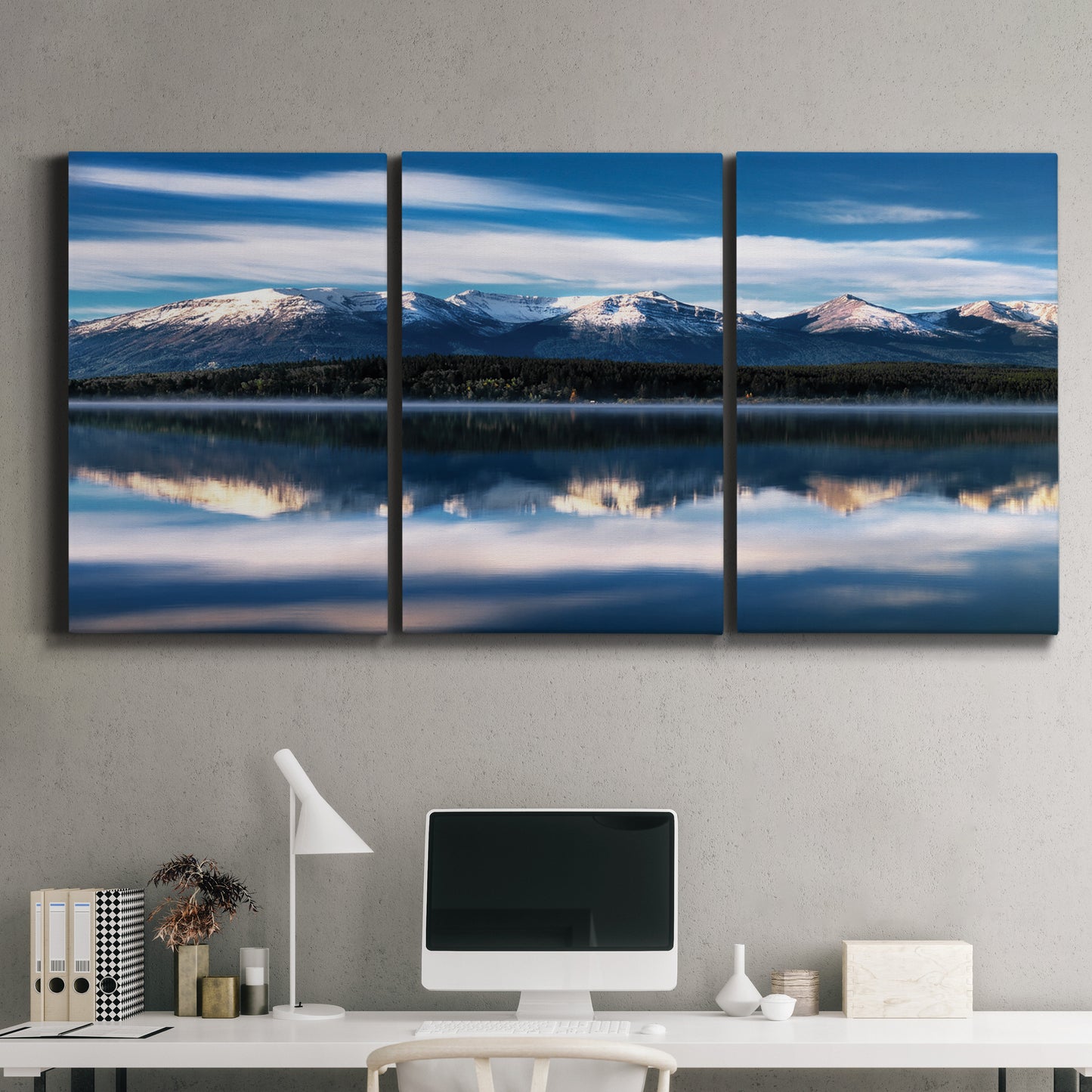 Three-panel canvas wall art featuring calm lake beneath mountains photograph, displayed above a desk in a home office.