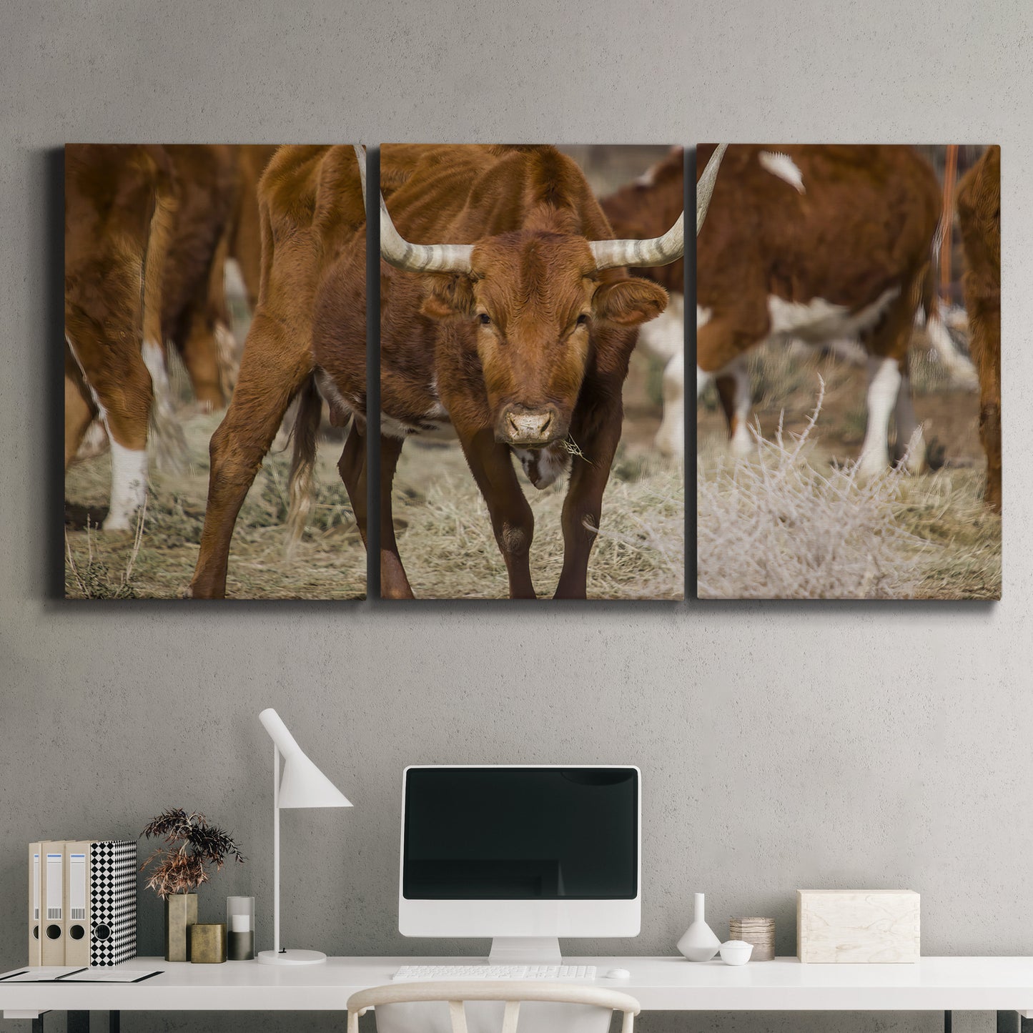 Three-panel canvas wall art featuring longhorn cattle standing together, displayed above a desk in a home office.